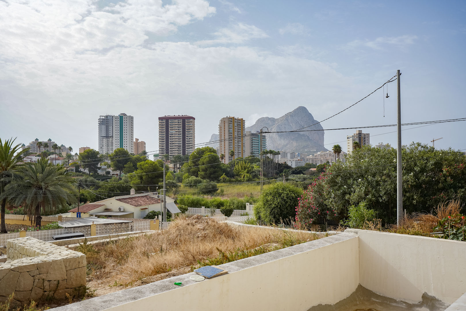 Vistas despejadas al Peñón de Ifach y al perfil urbano de Calpe desde la parcela elevada de la futura villa, rodeada de vegetación mediterránea.