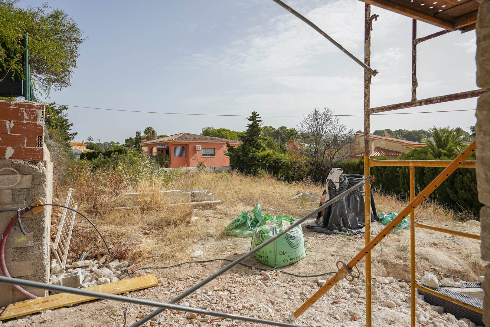 Vista de la parcela llana en Partida La Merced durante la fase inicial de construcción, rodeada de un entorno residencial tranquilo cerca de la costa de Calpe.