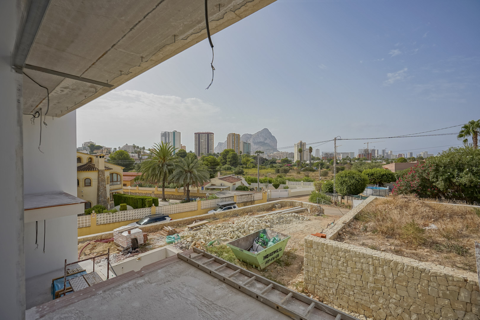 Vista panorámica desde la planta superior en construcción, capturando el Peñón de Ifach y el skyline de Calpe sobre la zona de jardín en desarrollo.