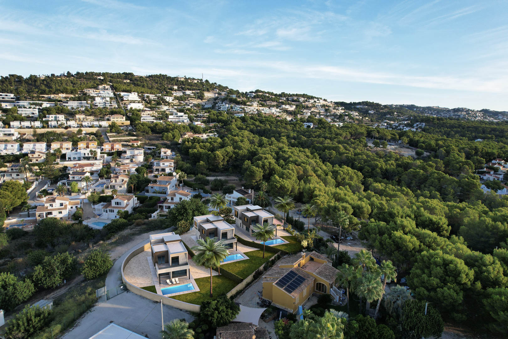 Vista aérea de las tres villas modernas con piscinas privadas y jardines, integradas en un entorno residencial rodeado de bosque de pinos en Calpe.