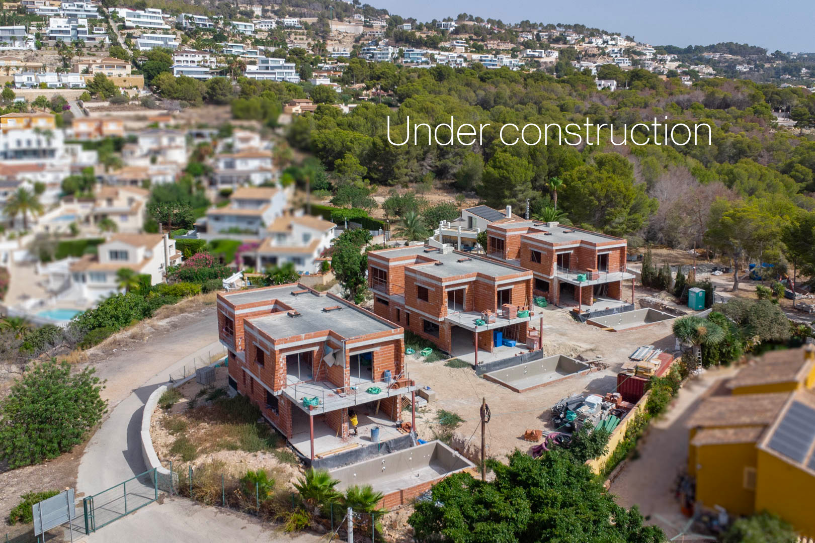 Vista aérea del estado actual de las tres villas en construcción, mostrando la estructura de ladrillo, las dos plantas y el foso de las piscinas privadas.