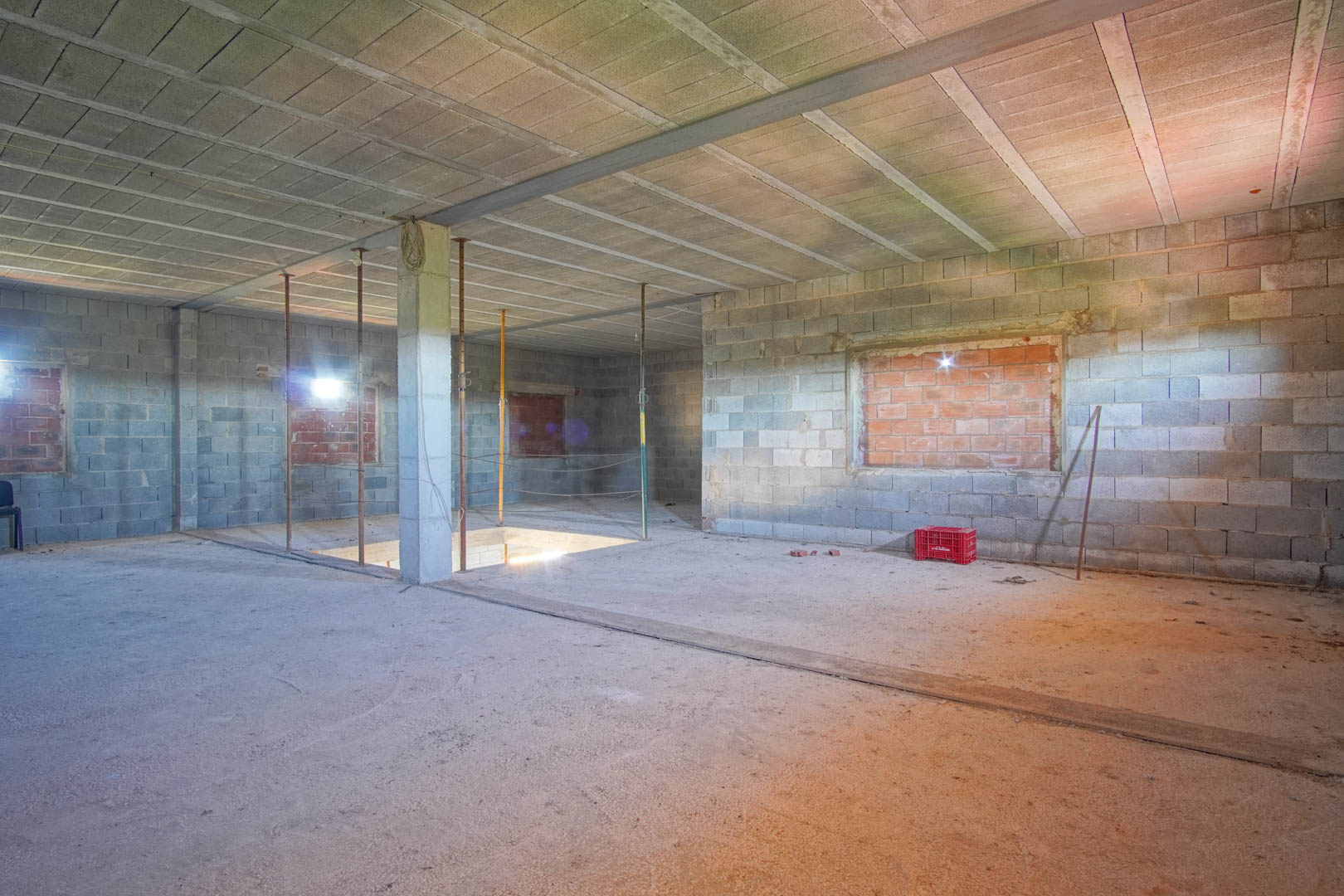 Planta diáfana en estado de obra con muros de bloque de hormigón, vigas de acero y hueco para escalera, lista para personalizar la distribución.