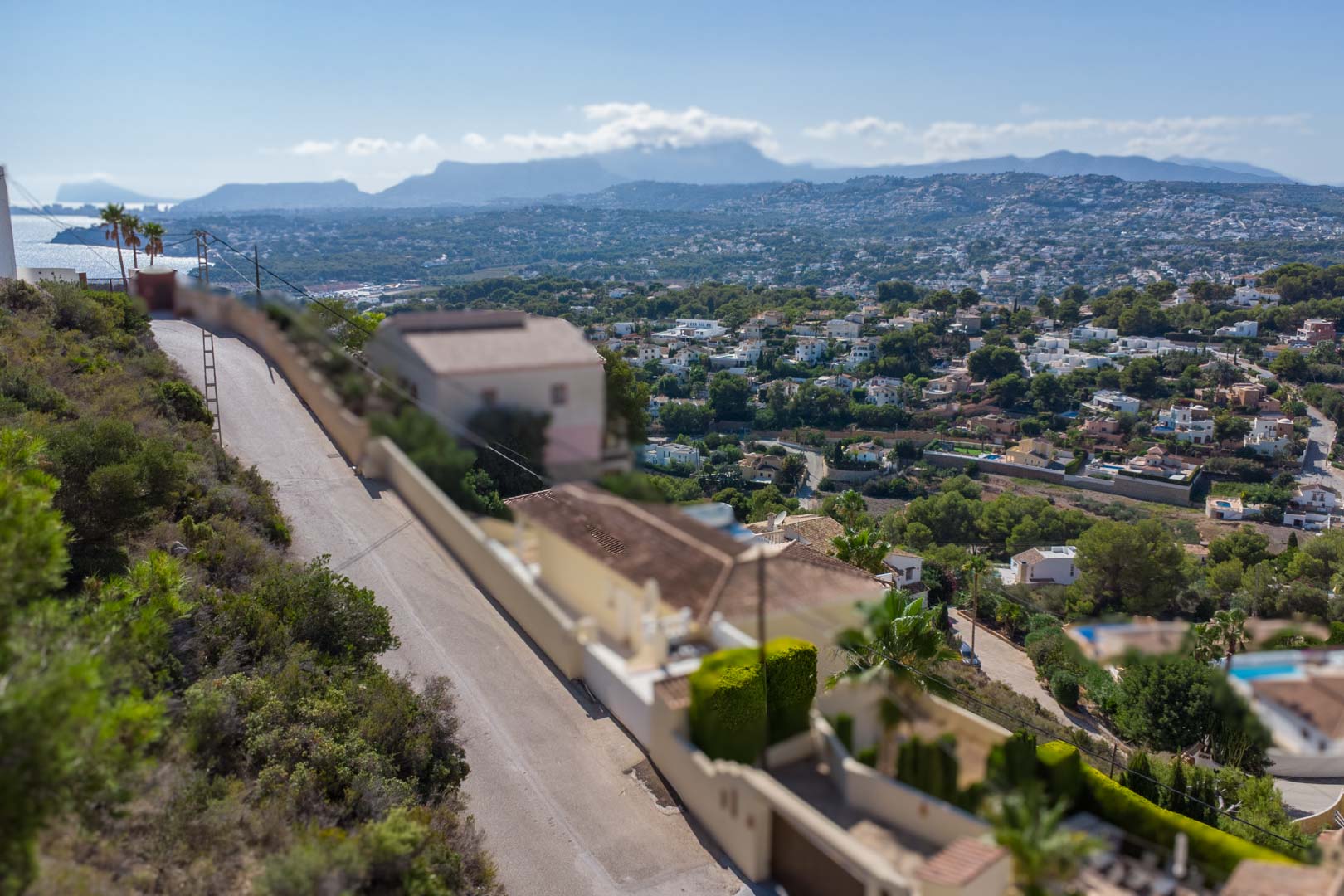 Vista panorámica elevada desde El Portet hacia la costa de Moraira y el mar Mediterráneo, con las montañas de la Marina Alta al fondo.