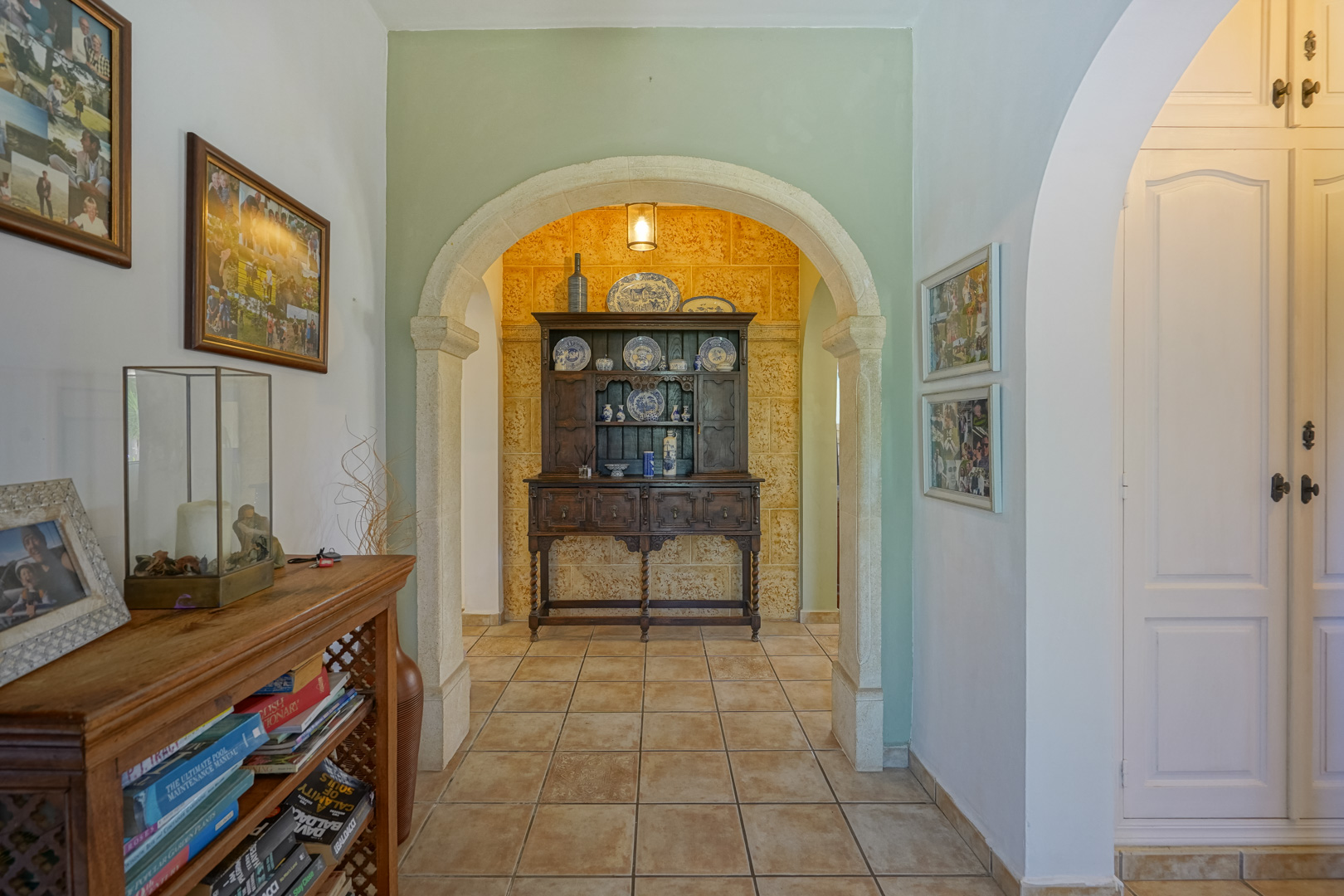 Detalle del recibidor con arco de piedra y mobiliario clásico de madera oscura.