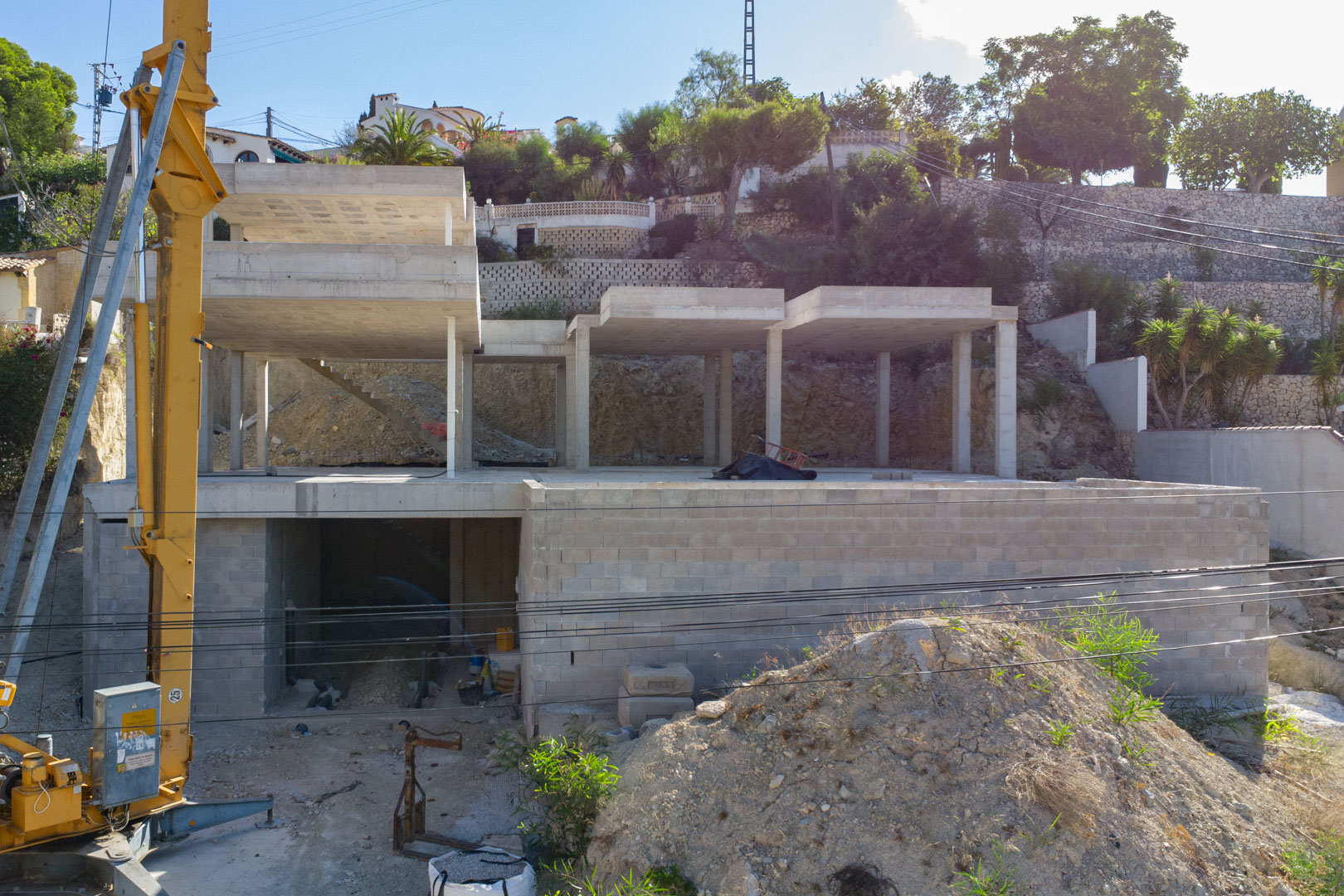 Vista de la estructura de hormigón armado en construcción en San Jaime, destacando los tres niveles de la vivienda y el acceso al garaje sobre la parcela elevada.