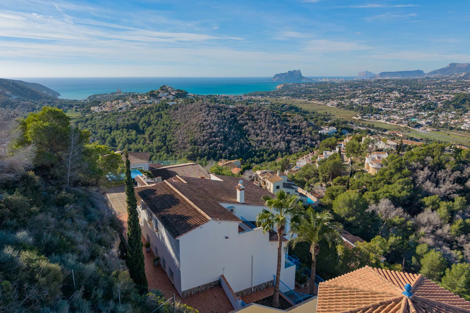 Vista aérea de la villa en Moraira, destacando su arquitectura mediterránea rodeada de pinos con vistas panorámicas al mar y al Peñón de Ifach.