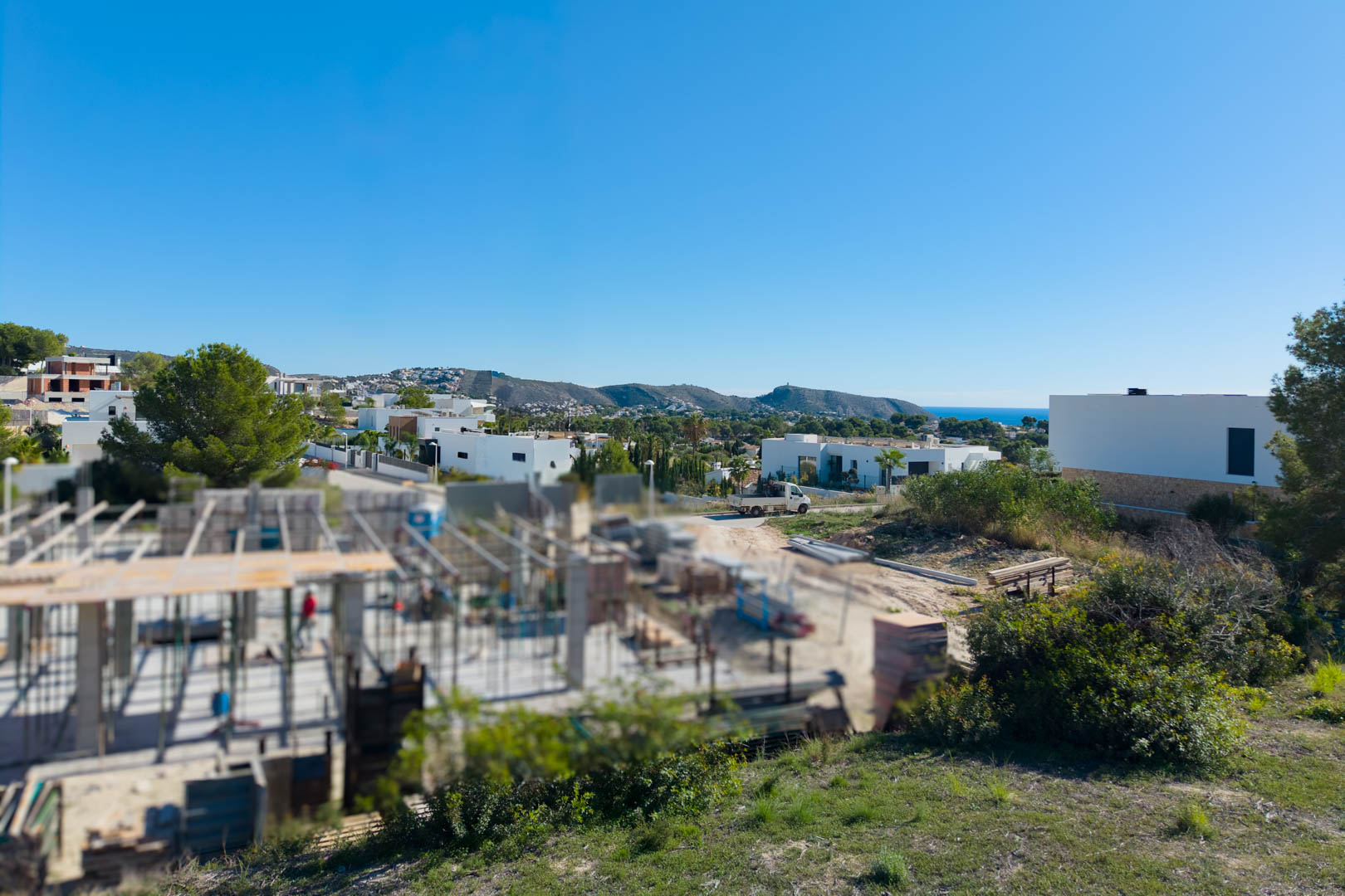 Vista panorámica desde la parcela en El Tesoro, mostrando el entorno residencial moderno, vistas al valle y el mar Mediterráneo en el horizonte.