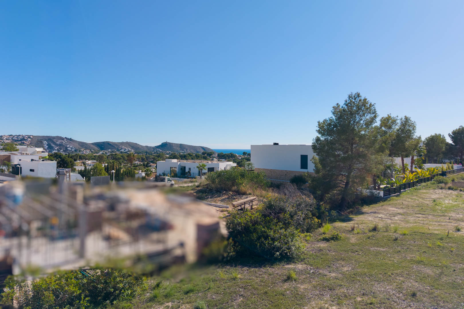 Vista panorámica desde la parcela urbana en El Tesoro, mostrando el terreno llano, villas modernas circundantes y vistas despejadas hacia el valle y el mar Mediterráneo.