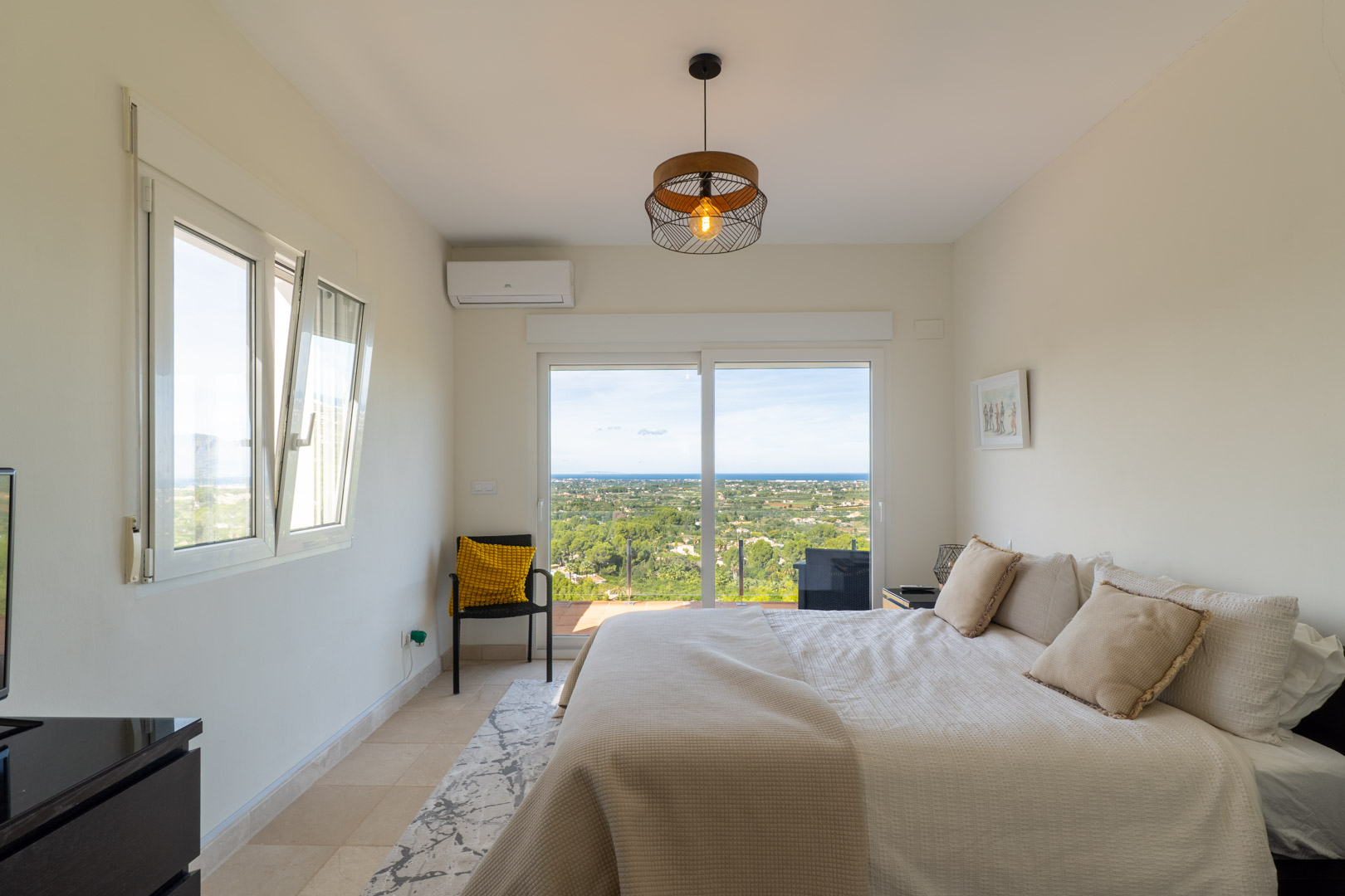 Dormitorio con acceso a terraza y vistas panorámicas al mar. Incluye aire acondicionado, suelos de gres y una amplia puerta corredera acristalada que aporta luz natural.