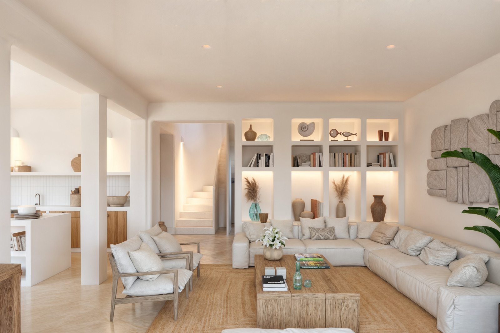 Salón de estilo ibicenco con estanterías integradas iluminadas, sofás en tonos neutros y mesa de madera maciza sobre alfombra de fibras naturales. Al fondo se aprecia la escalera.