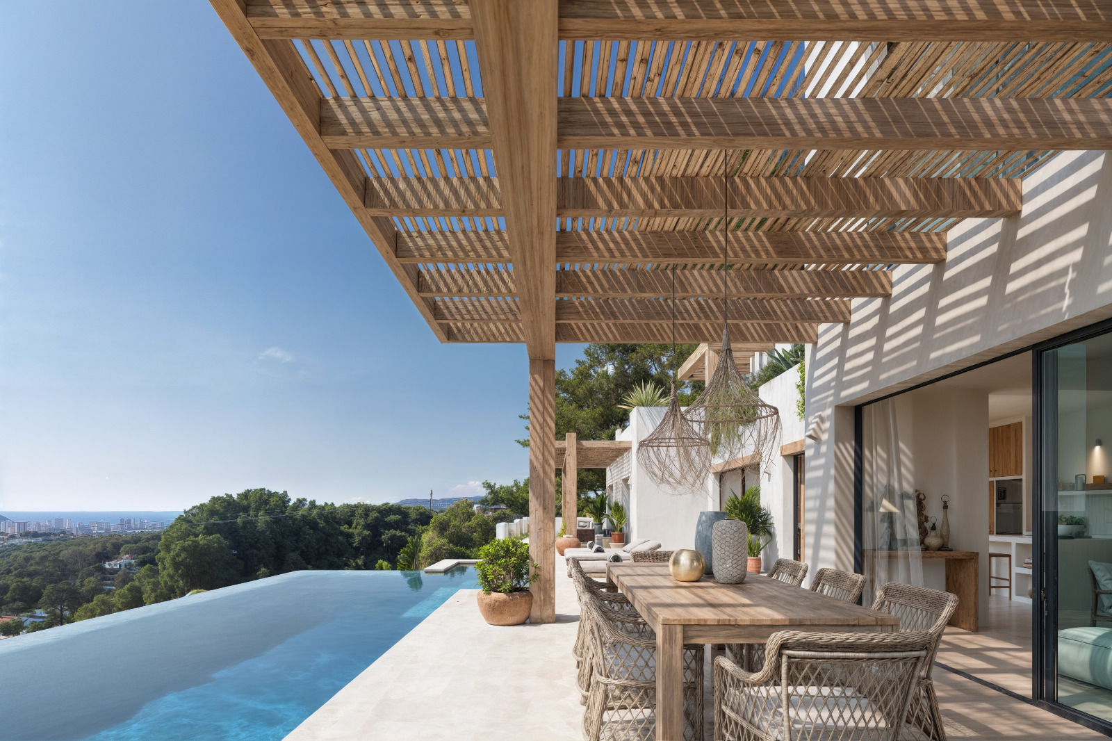 Terraza exterior con pérgola de madera, zona de comedor y piscina infinita con vistas panorámicas al mar Mediterráneo y la costa de Benissa.