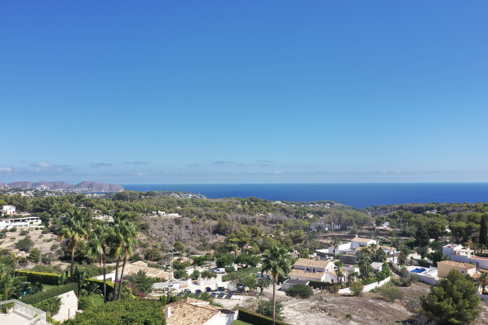 Vista panorámica elevada desde Racó de Galeno hacia el mar Mediterráneo, mostrando la vegetación costera y las villas residenciales de Benissa bajo un cielo despejado.