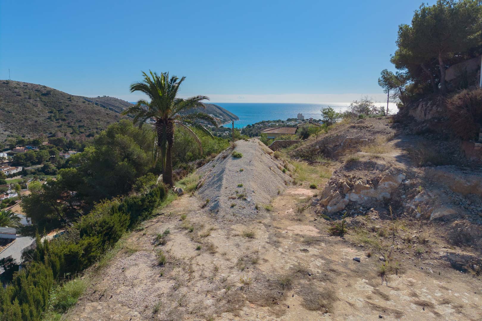 Vista panorámica desde la parcela elevada hacia la bahía de El Portet, destacando el entorno natural y la amplitud visual hacia el mar Mediterráneo en Moraira.