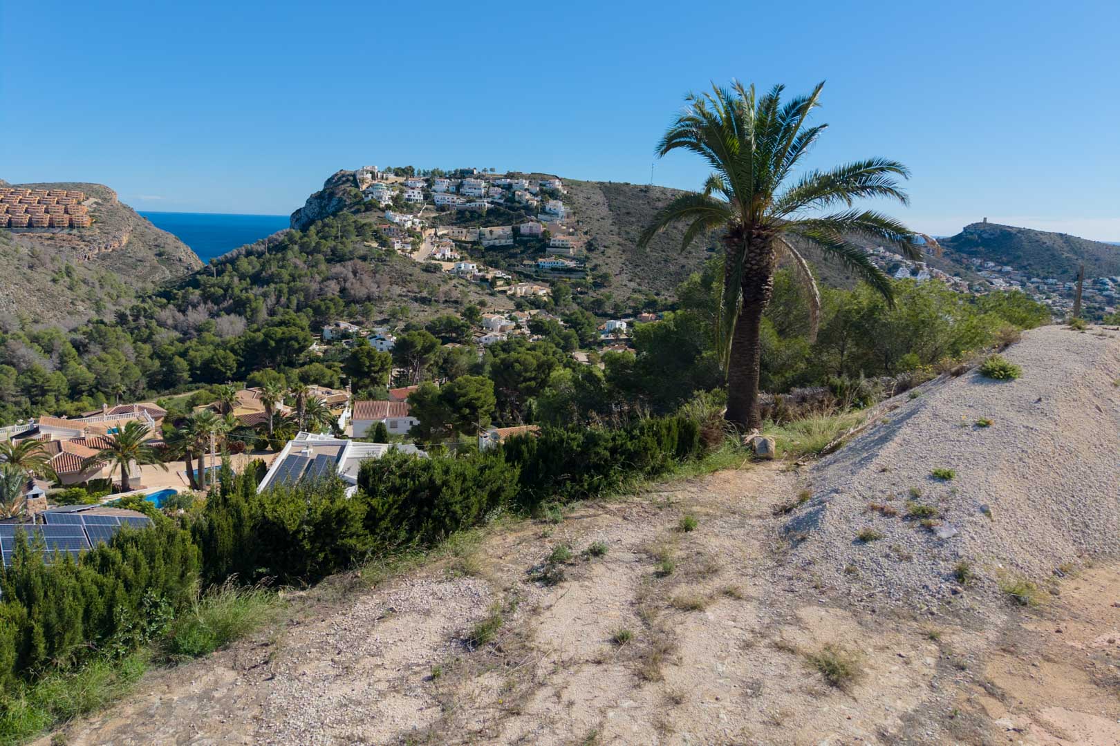 Vistas panorámicas desde la parcela elevada hacia el valle de Moraira, con el mar Mediterráneo al fondo y colinas pobladas de vegetación autóctona.