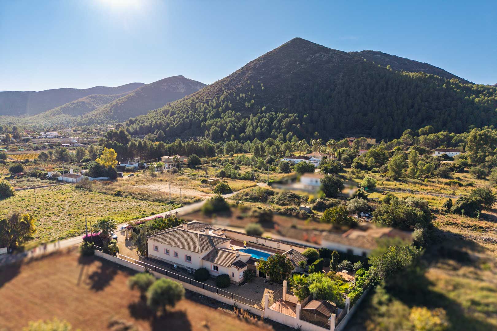 Vista aérea de la villa mediterránea en Jalón, mostrando la piscina privada integrada y el entorno natural rodeado de montañas.
