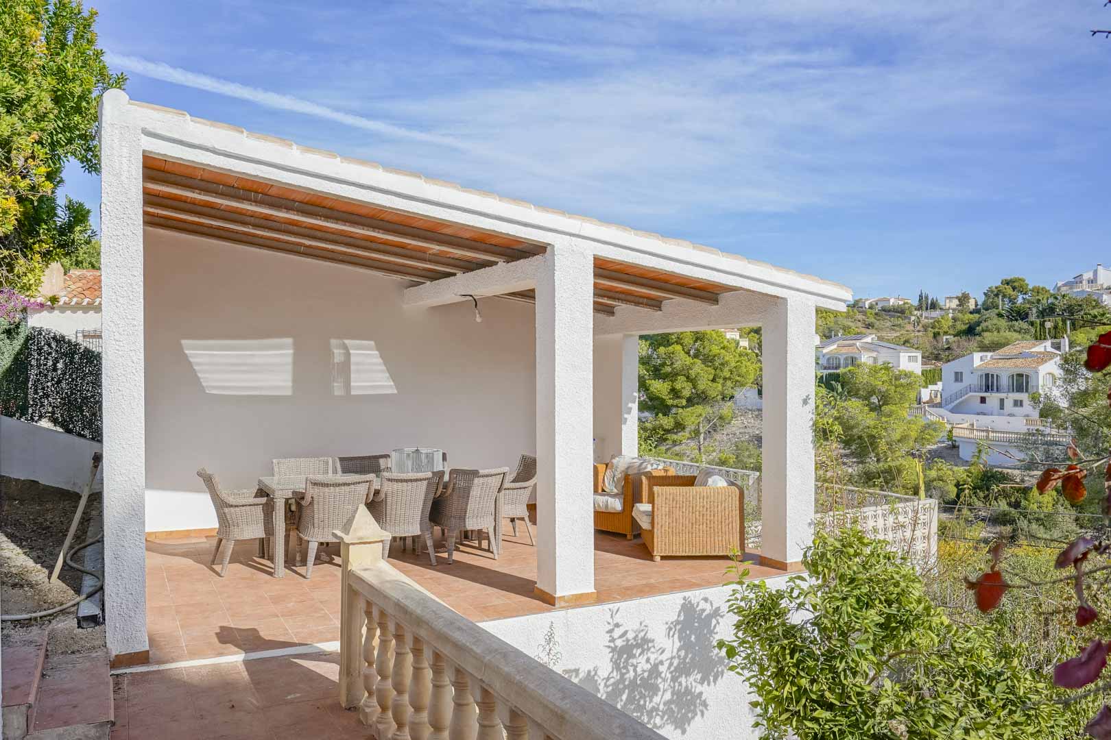 Terraza elevada y cubierta con techo de vigas de madera, mobiliario de mimbre y vistas despejadas al entorno natural de Pinomar.