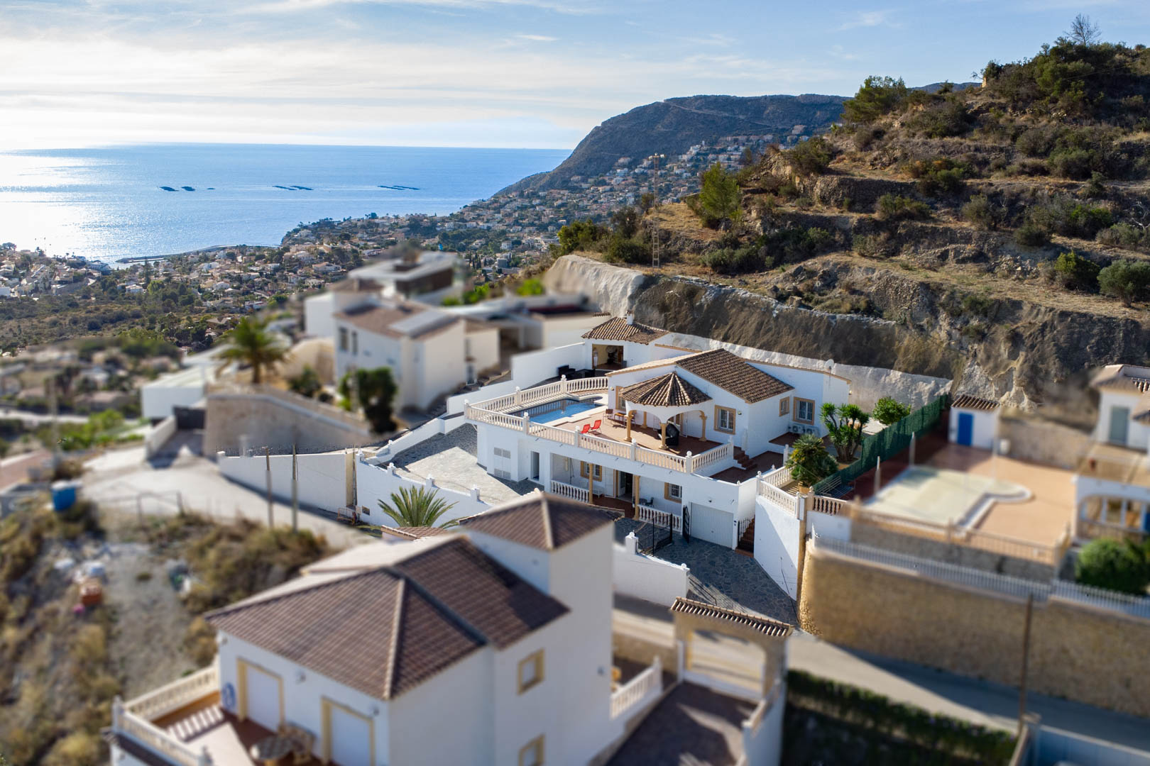 Vista aérea de la villa en Partida Cucarres, destacando la terraza con piscina, el tejado de teja tradicional y las vistas panorámicas al mar Mediterráneo y la costa.