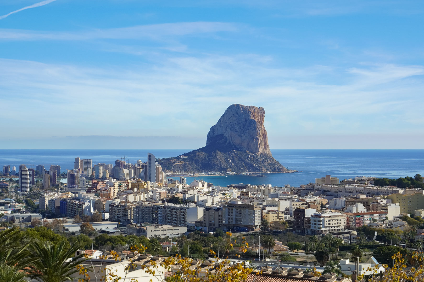 Vista panorámica del Peñón de Ifach y el skyline de Calpe desde una posición elevada, destacando la costa mediterránea y el entorno urbano costero.
