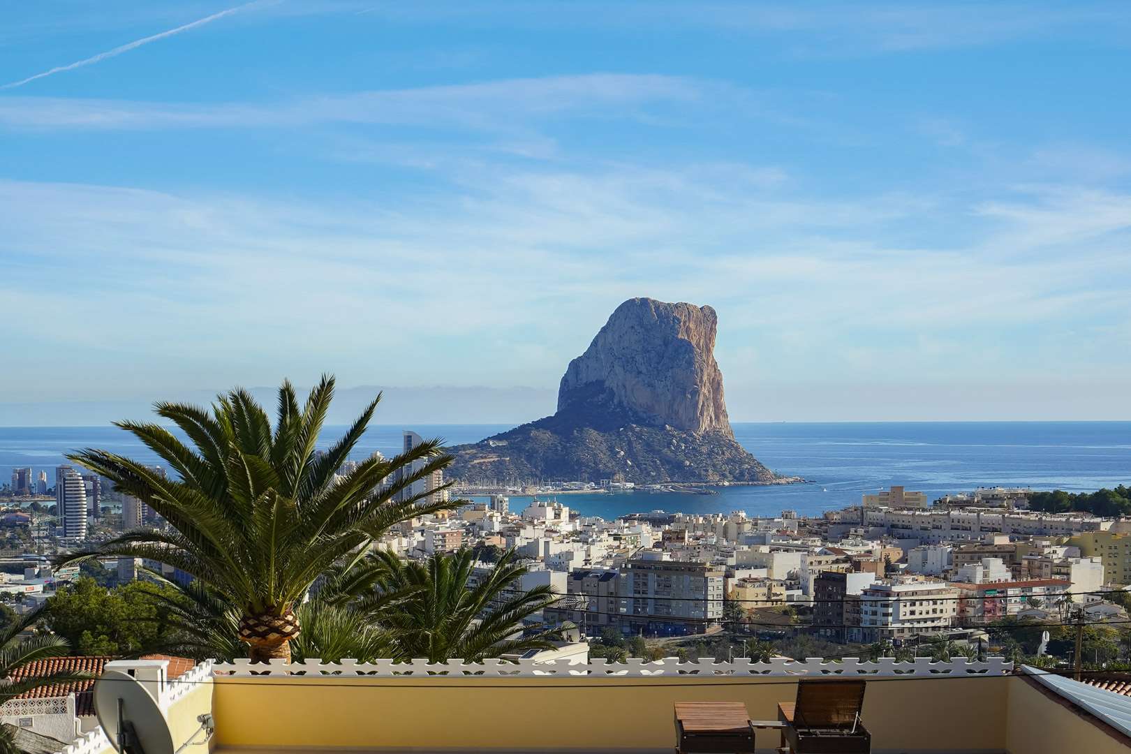 Vista panorámica desde la terraza hacia el Peñón de Ifach y el skyline de Calpe, con el mar Mediterráneo de fondo y mobiliario de descanso en primer plano.