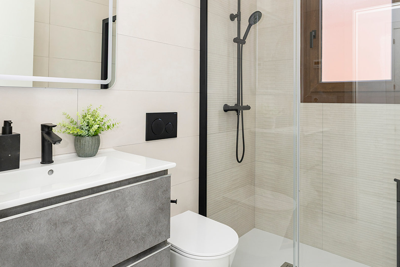 Baño moderno con mueble gris, grifería negra mate, inodoro suspendido y zona de ducha con mampara de cristal y azulejos de relieve lineal.
