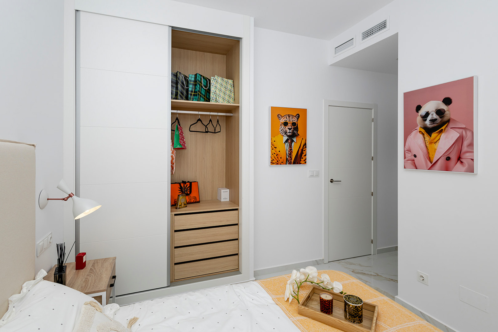 Dormitorio con armario empotrado de puertas correderas blancas e interior de madera. Incluye suelos de gres efecto mármol y climatización por conductos.
