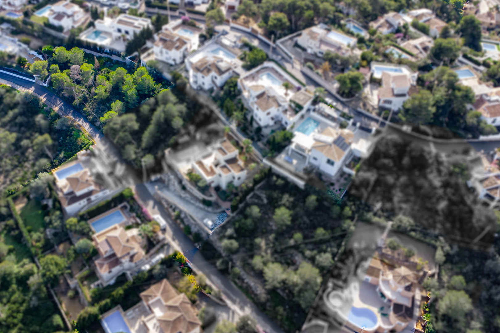 Vista aérea de la parcela de 1521 m2 con vegetación autóctona, situada en una ladera elevada junto a villas residenciales en la zona de Granadella-Ambolo.