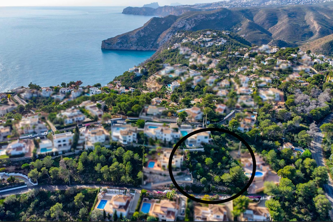 Vista aérea de la parcela de 1042m² rodeada de pinos en la zona de Ambolo, con vistas despejadas hacia el mar Mediterráneo y los acantilados de Jávea.