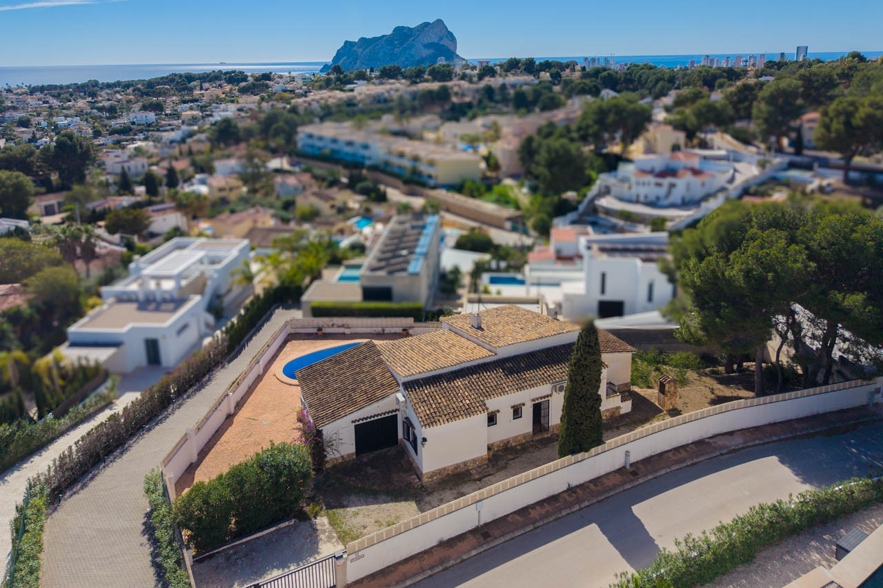 Vista aérea de la villa con arquitectura mediterránea tradicional, piscina privada y vistas despejadas hacia el mar y el Peñón de Ifach en Calpe.