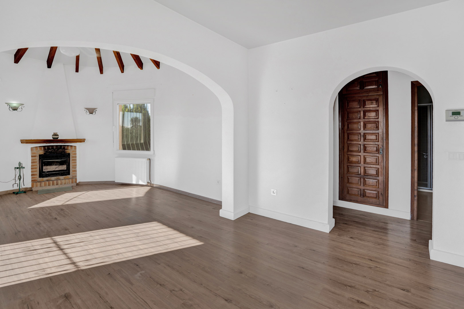 Salón luminoso con chimenea de ladrillo, vigas de madera vistas y suelos laminados. Dispone de arcos arquitectónicos, calefacción por radiadores y carpintería interior de madera noble.