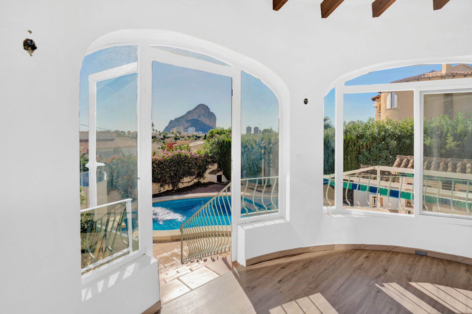 Terraza acristalada con suelos de tarima, vigas de madera y amplios ventanales que ofrecen vistas directas al Peñón de Ifach y a la zona de la piscina privada.