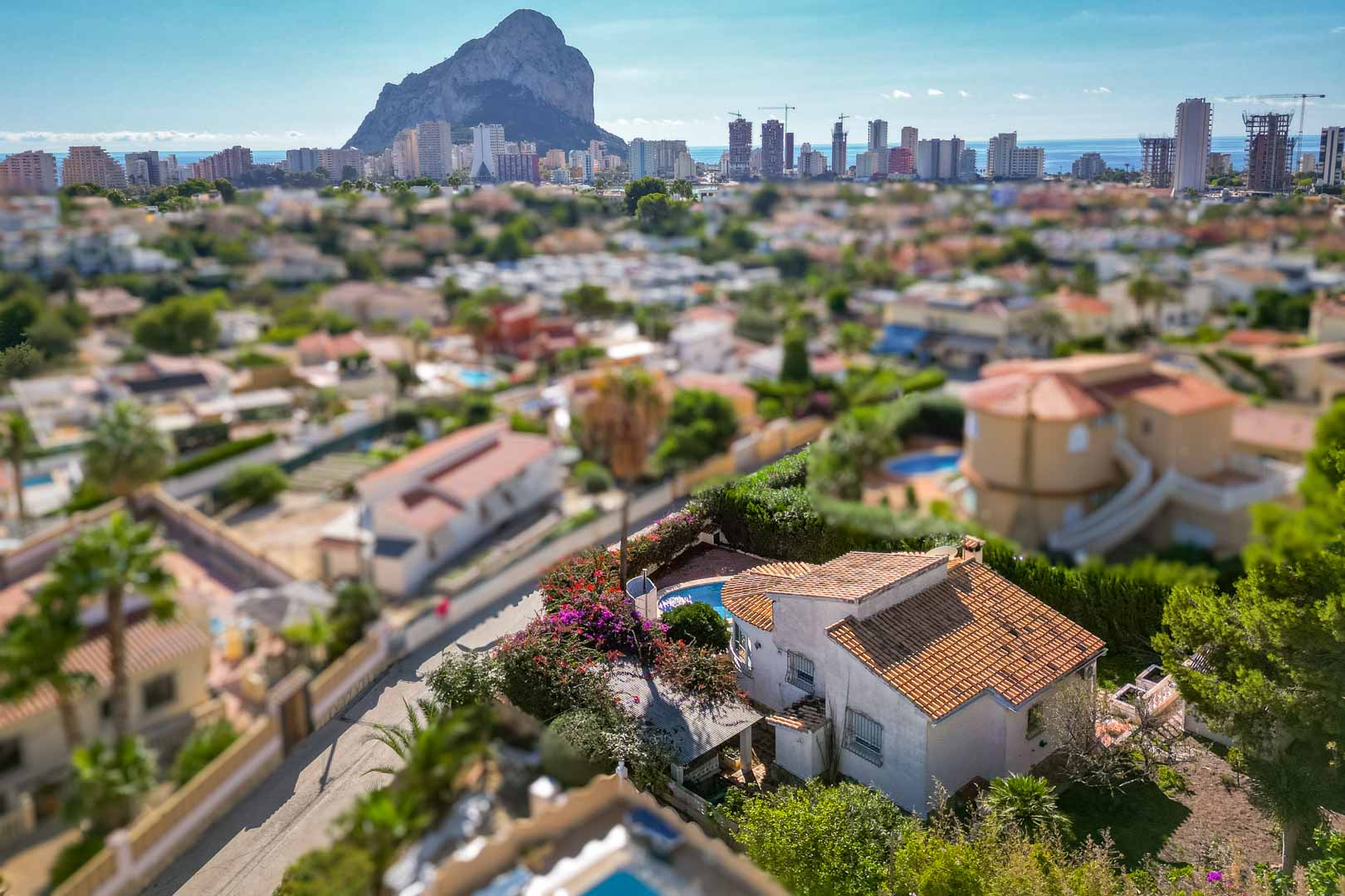 Vista aérea de la propiedad con piscina privada y jardín, destacando las vistas panorámicas al Peñón de Ifach y el perfil urbano de Calpe.