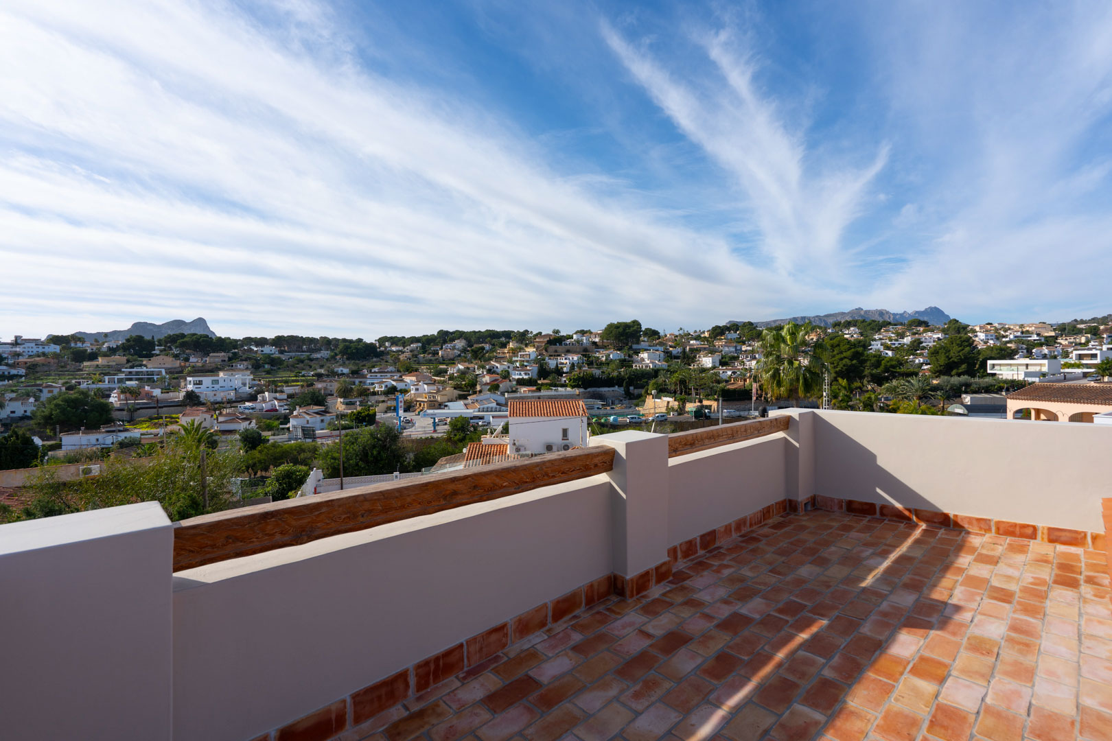 Azotea con suelo de terracota y vigas de madera, ofreciendo vistas panorámicas al Peñón de Ifach, la Sierra de Bernia y el entorno residencial de Benissa.