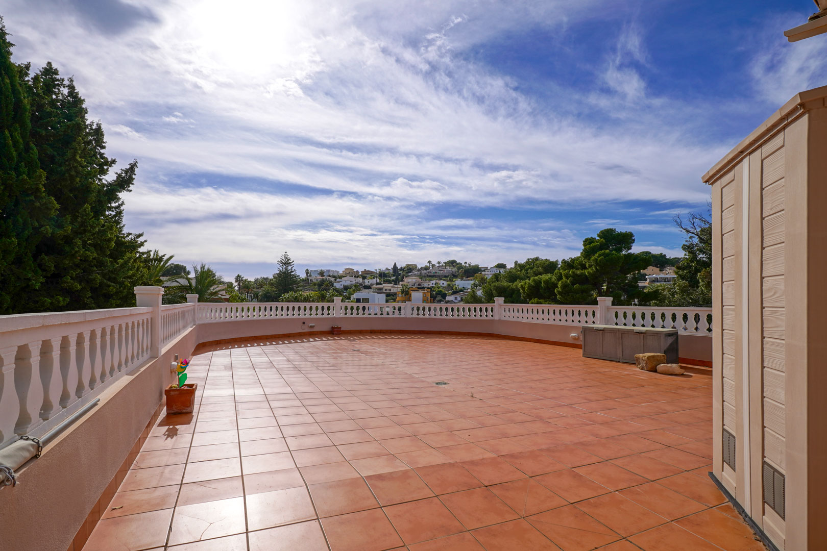 Amplia terraza exterior con suelo de baldosas de terracota y balaustrada blanca, ofreciendo vistas despejadas al entorno natural y residencial de Benissa.