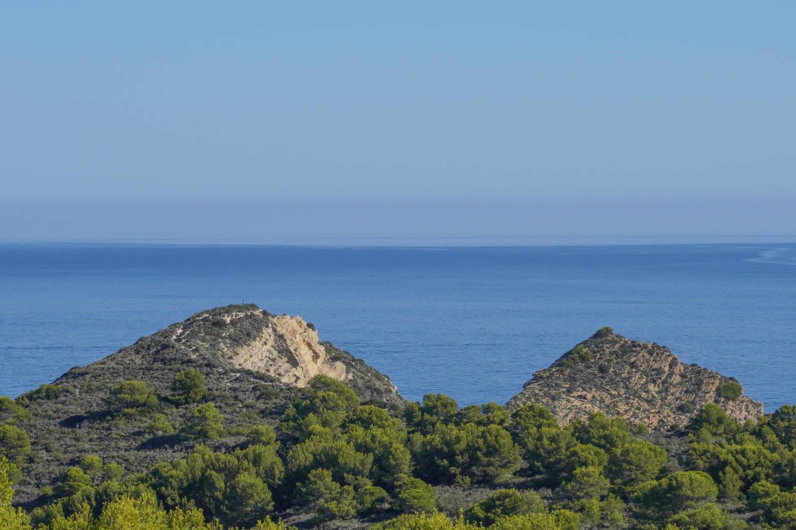 Vistas panorámicas al mar Mediterráneo desde la propiedad, destacando la costa virgen con colinas rocosas y densos pinares bajo un cielo despejado.