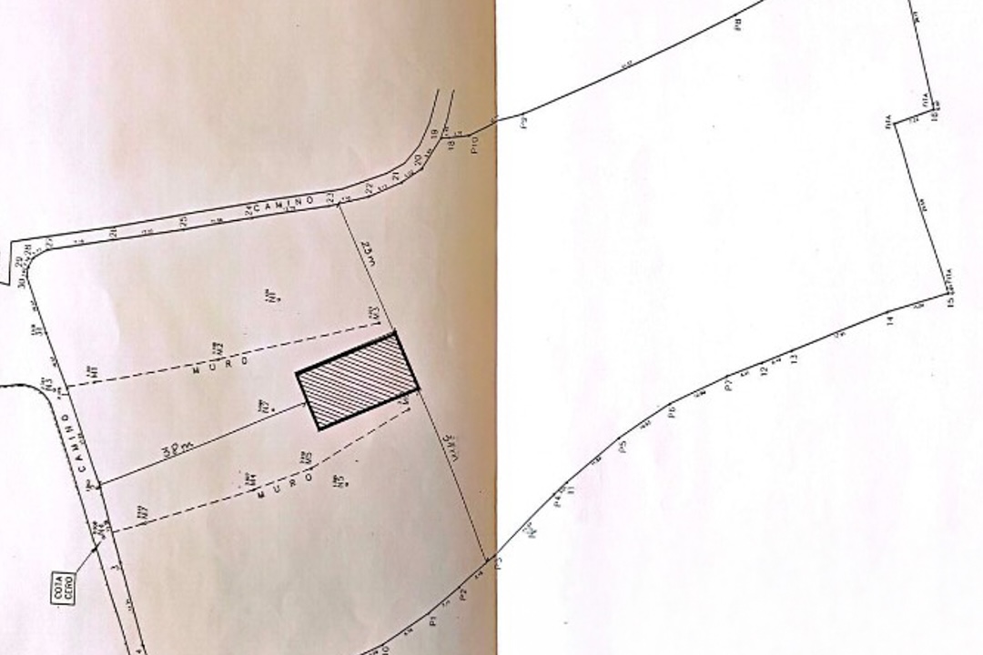 Plano técnico que muestra los límites de la parcela, el acceso por camino y la huella sombreada de una edificación con medidas métricas detalladas.