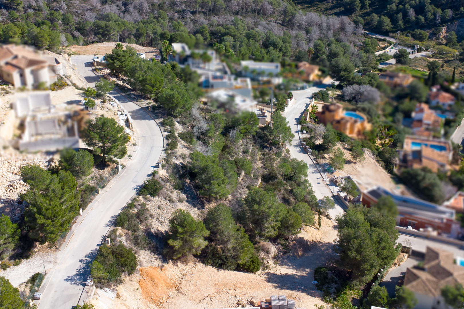 Vista aérea de la urbanización Tosalet 5 en Jávea, mostrando viales asfaltados, parcelas elevadas rodeadas de pinos y viviendas unifamiliares integradas en el paisaje.