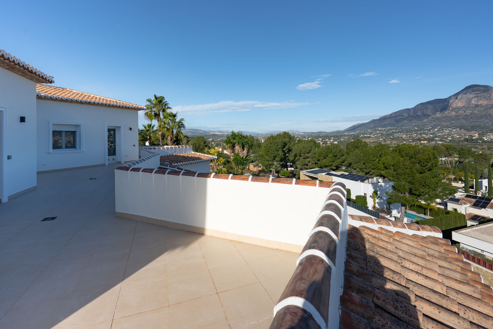 Terraza superior con pavimentos cerámicos en tonos arena y vistas despejadas al macizo del Montgó y al entorno natural mediterráneo.
