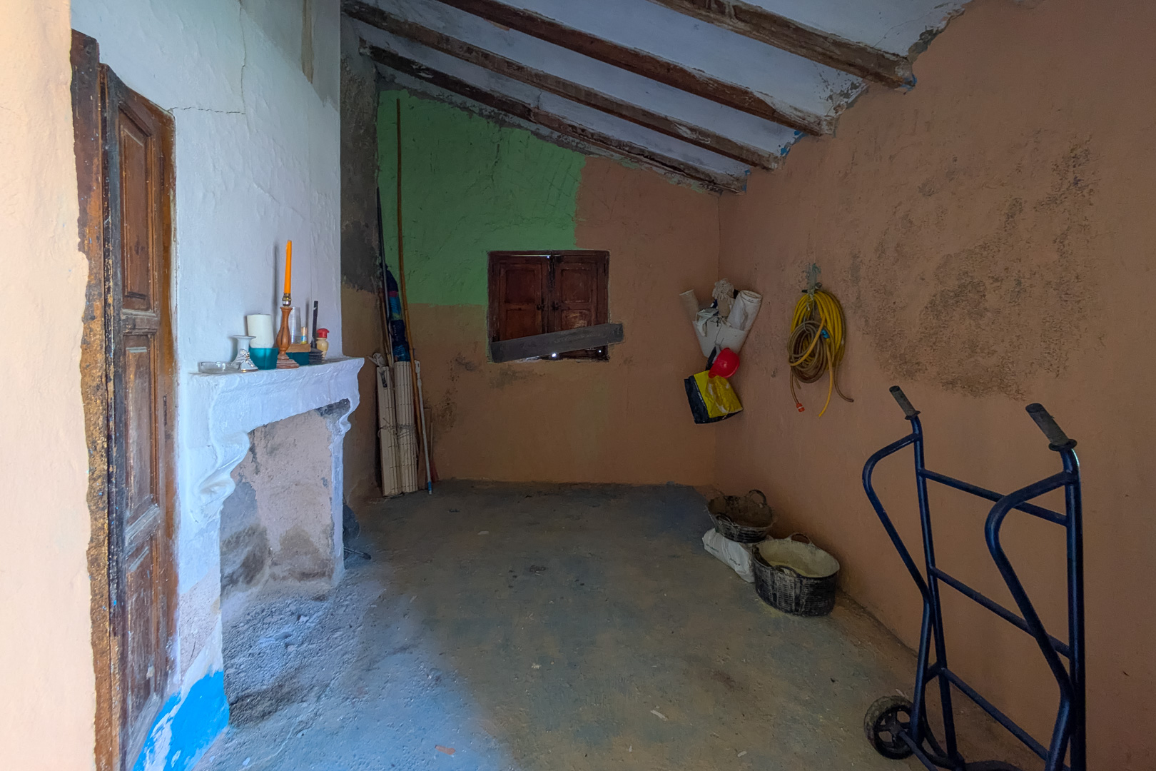 Interior rústico con chimenea de obra, techos de vigas de madera inclinadas y paredes de yeso texturizado en tonos tierra, ideal para reforma integral.