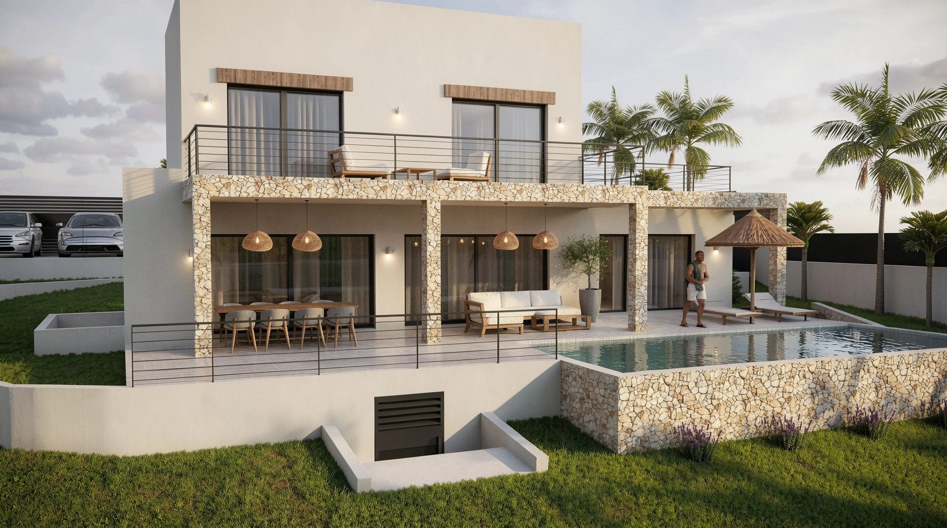Fachada posterior de la villa con revestimiento de piedra natural, terraza cubierta con zonas de estar y comedor, piscina privada y balcón superior con barandilla metálica.