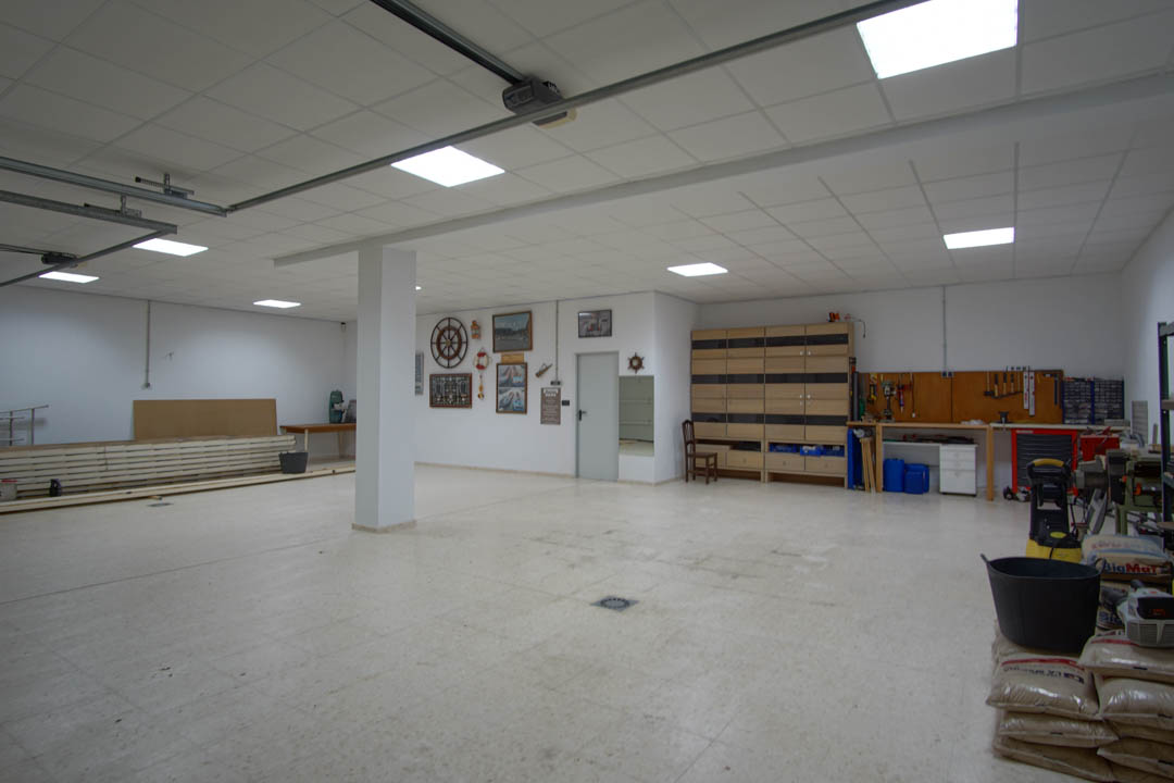 Amplio garaje con capacidad para cinco vehículos, equipado con zona de taller, paneles de iluminación LED empotrados y techos técnicos.