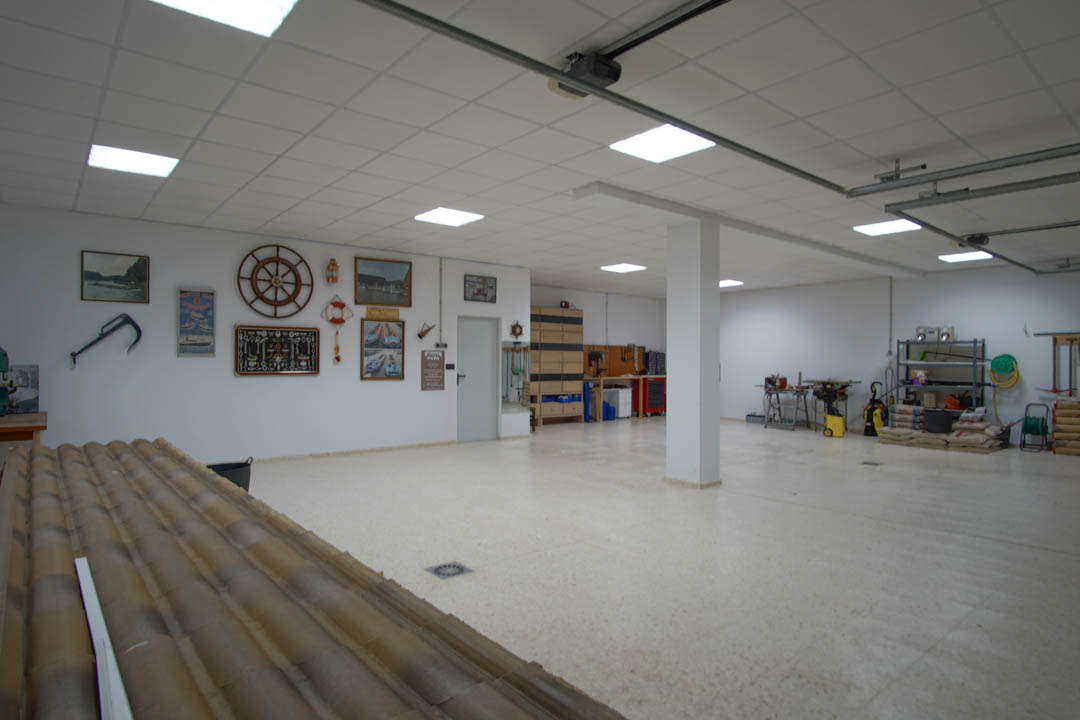 Amplio garaje para cinco vehículos con techos técnicos, iluminación LED integrada y una zona de taller equipada, decorado con motivos náuticos clásicos.