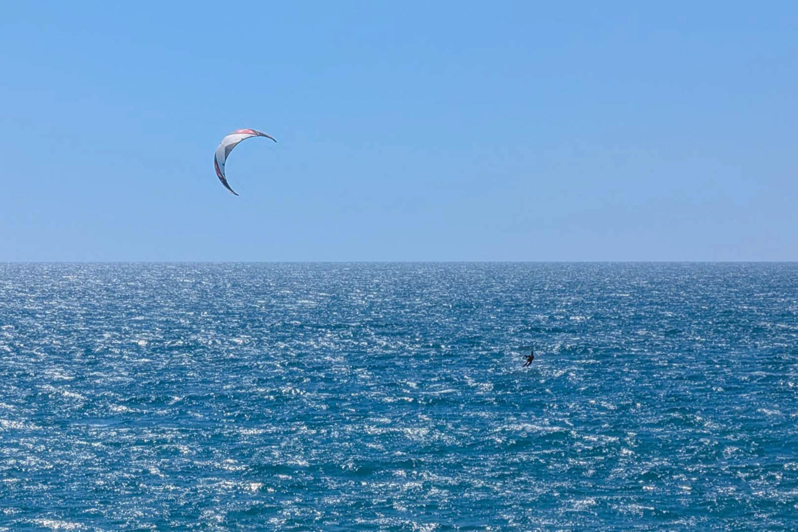 Vista panorámica del mar Mediterráneo frente a la costa de Calpe, donde se aprecia la práctica de kitesurf bajo un cielo despejado.