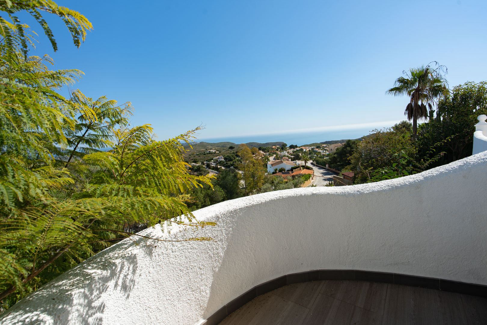 Terraza con muro curvo de acabado rugoso blanco y suelo cerámico, ofreciendo vistas panorámicas al mar Mediterráneo y al entorno residencial de Cumbre del Sol.