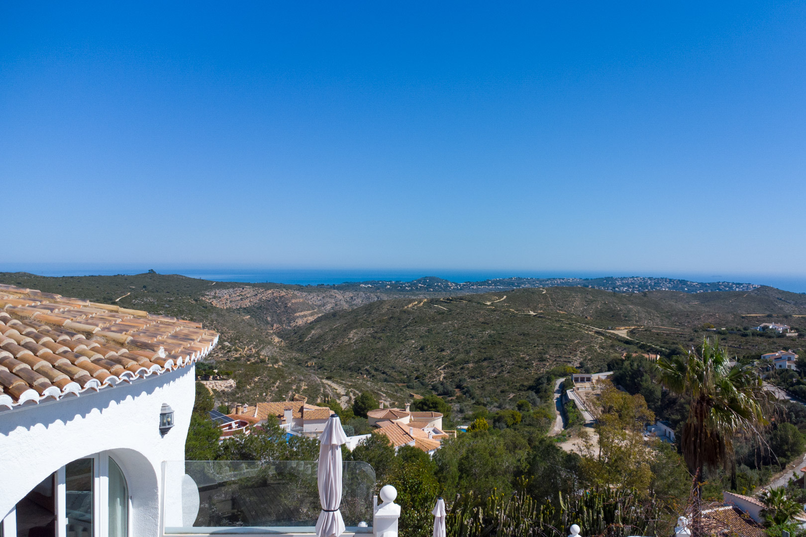 Vista panorámica desde la villa hacia el parque natural de la Granadella y el mar Mediterráneo, destacando la arquitectura tradicional de teja y fachadas blancas.