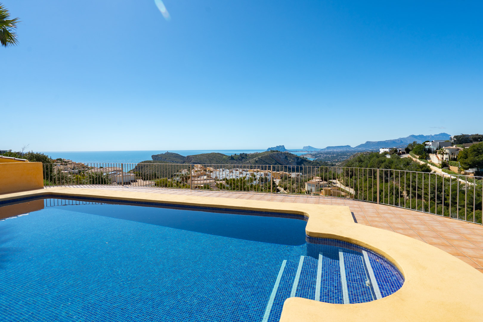 Terraza con piscina de gresite azul y vistas panorámicas al mar Mediterráneo, el Peñón de Ifach y la Sierra de Bernia desde Cumbre del Sol.