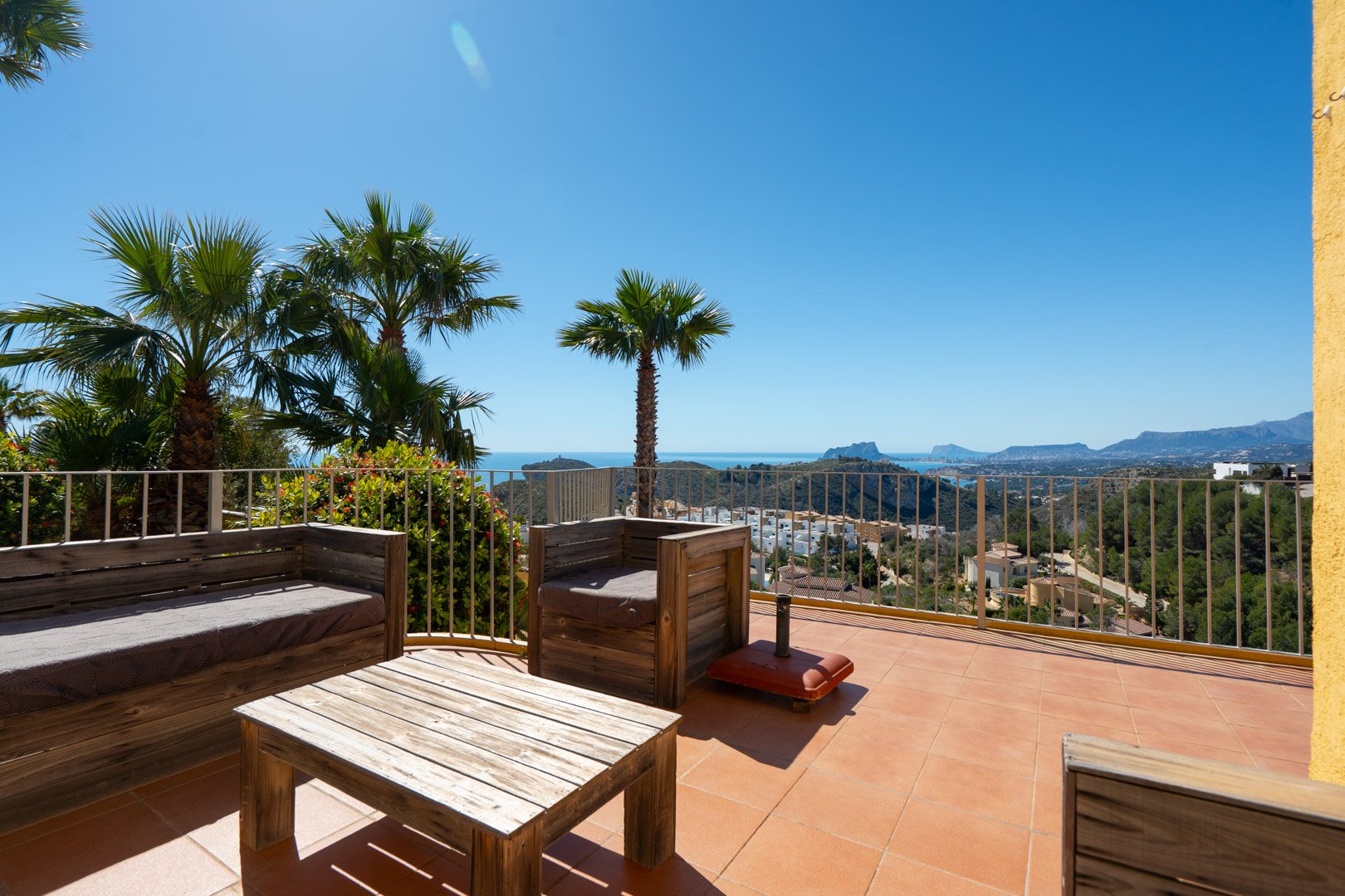 Terraza solárium con mobiliario de madera rústica y vistas panorámicas al mar Mediterráneo, el Peñón de Ifach y la costa de Calpe.