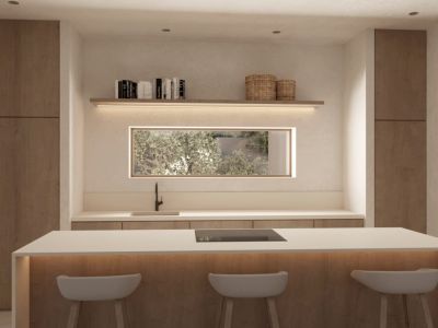 Isla de cocina moderna con placa integrada, encimera blanca y tres taburetes. Presenta armarios de madera, ventana rectangular con vistas al jardín y estanterías iluminadas.