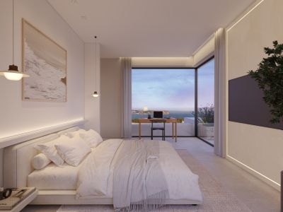 Amplio dormitorio con cama king-size, iluminación integrada y escritorio moderno. Ventanales de suelo a techo ofrecen vistas panorámicas al mar y la costa, complementado con TV y luz ambiental.