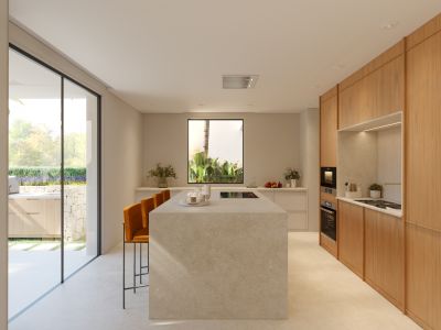 Cocina moderna con isla central de piedra, encimera de inducción integrada y barra con taburetes. Armarios de madera clara y acceso a cocina exterior.