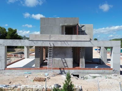 Estructura de hormigón de la villa en fase inicial de construcción, mostrando el esqueleto y aberturas para ventanales.